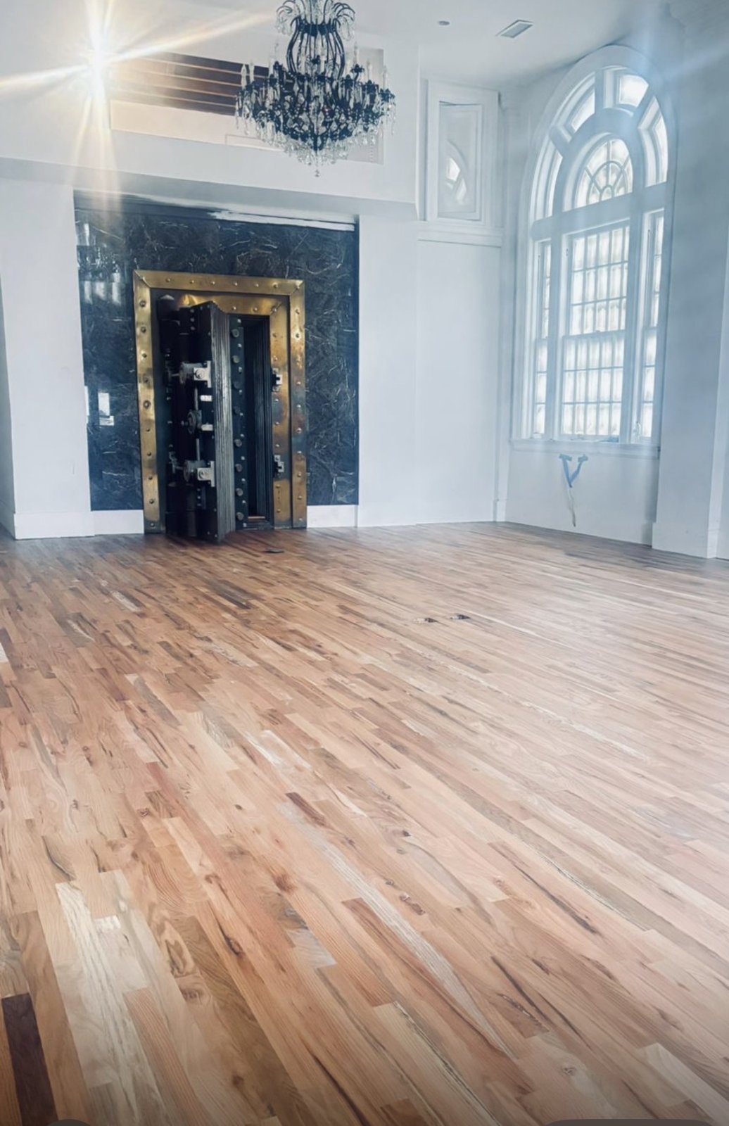 Restored banking hall with original vault, chandelier, and new hardwood floors