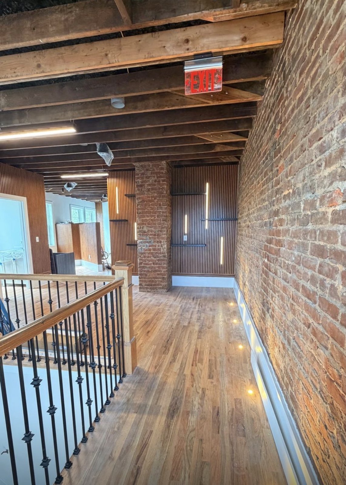 Mezzanine level with exposed brick, timber beams, and wood slat paneling